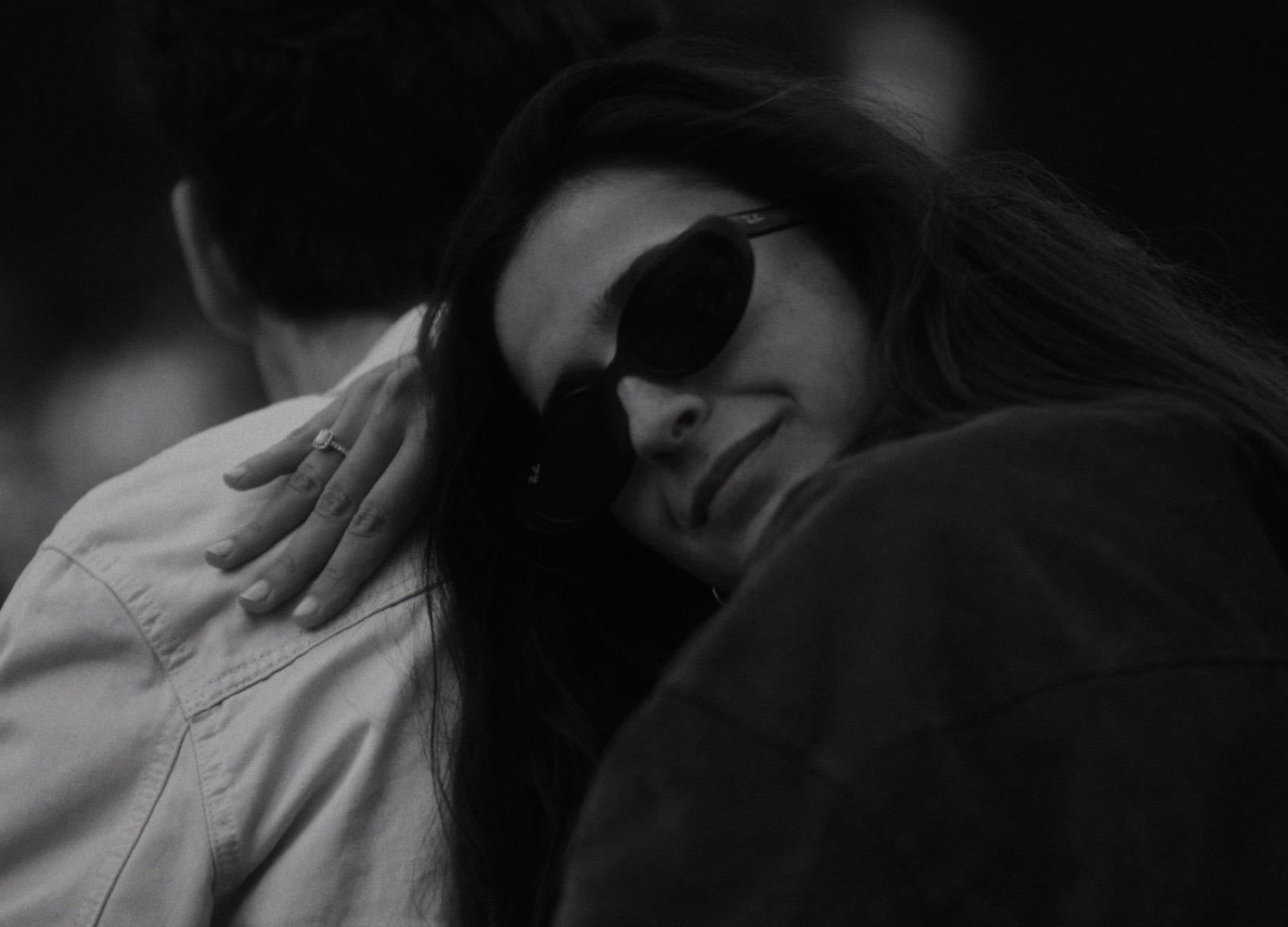 En blanco y negro: la mano de Rebeca, con el anillo de pedida, sobre el hombro de Alejandro